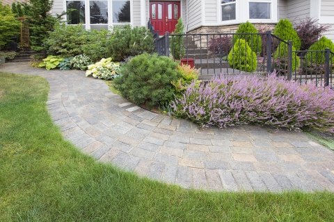 Custom Designed Landscaping With Stone Path, Shrubs, Patio, And Beautiful Multi-colored Flowers