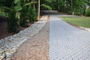 Custom Designed Landscaping With Stone Pathway, Pebble Gutter, Trees, Mulch, And Manicured Lawn