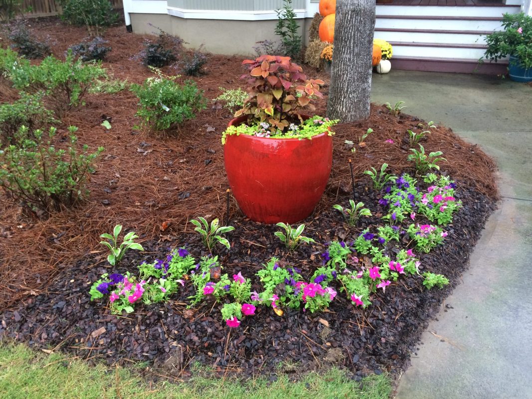 Custom Designed Landscaping With Red Planter, Flowers, And Shrubs